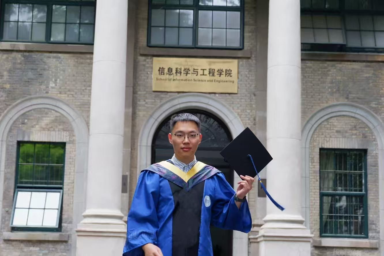 Zhiyuan Yu in graduation gown in front of the School of Information Science and Engineering