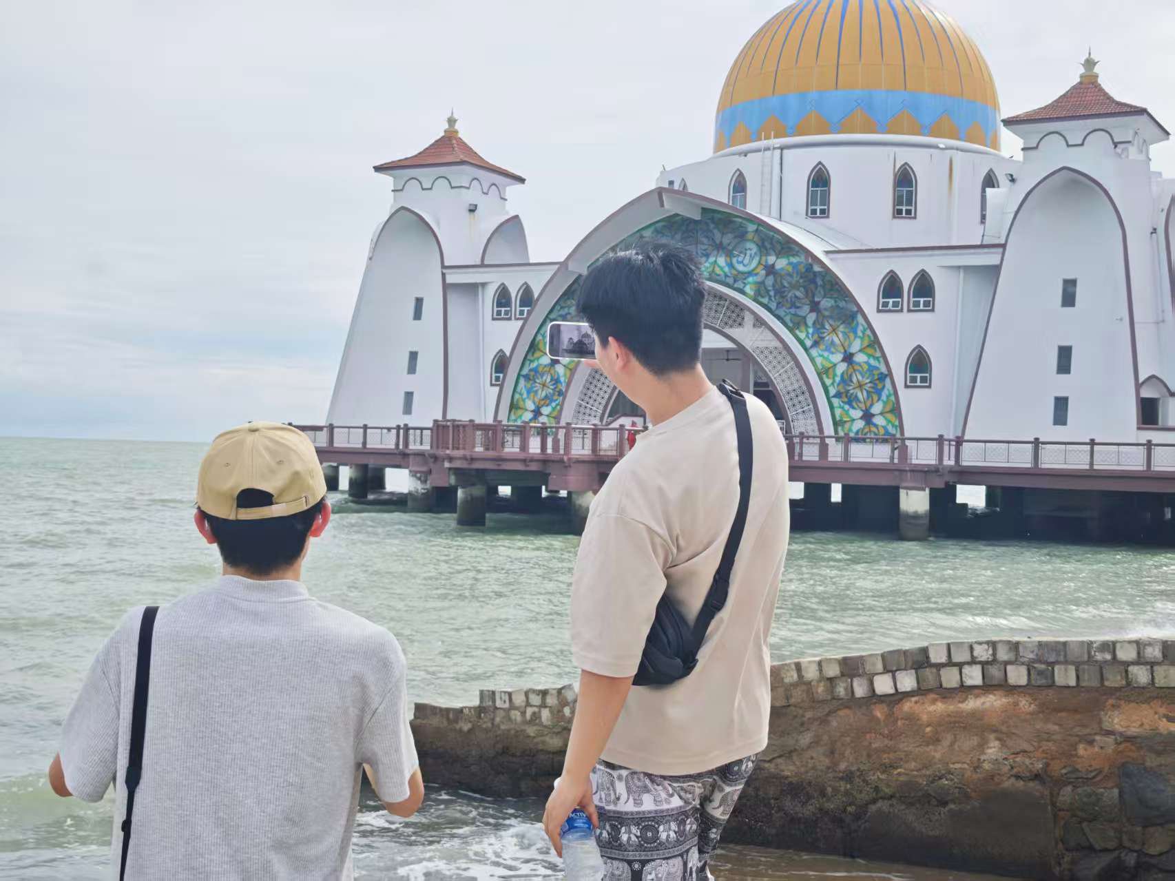 两位游客站在马六甲海上清真寺前拍照